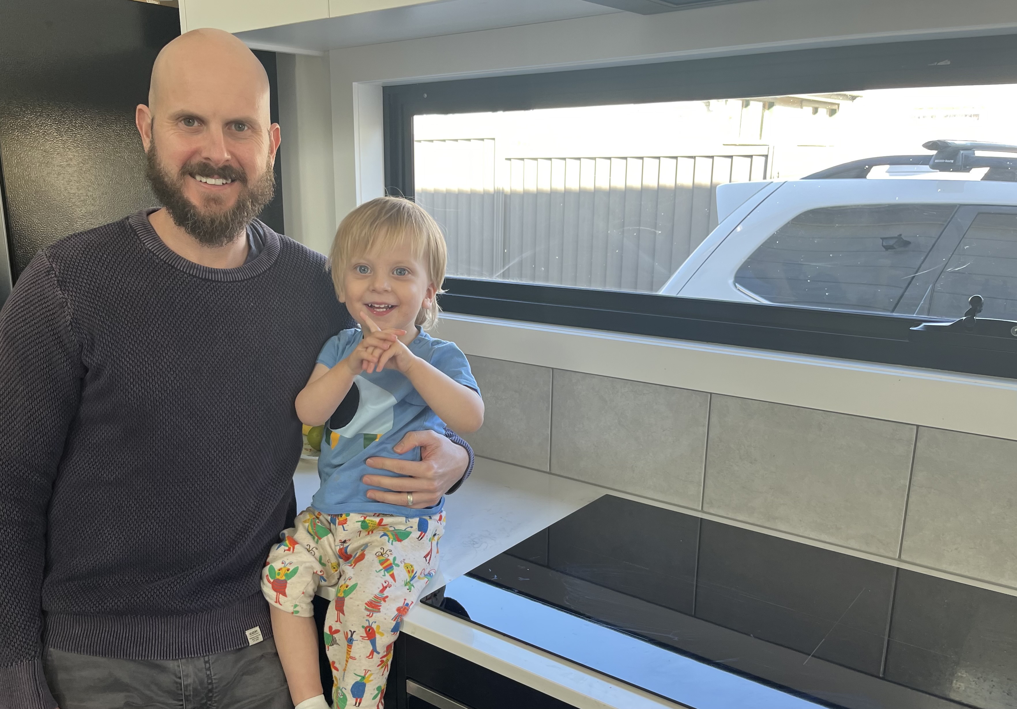 Mat and son sitting in kitchen near induction cooktop